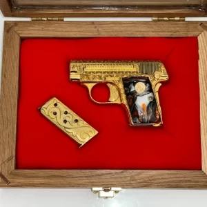 Custom gold-plated Colt pocket pistol with engraved grip in red velvet display case.