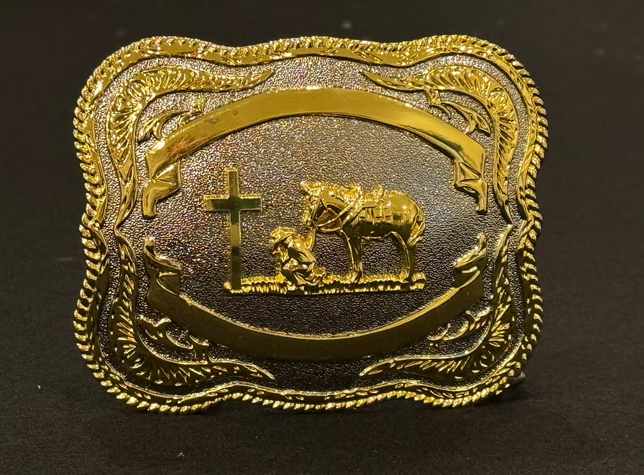 A belt buckle featuring a detailed depiction of a cowboy kneeling in prayer.