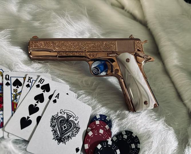 A custom handgun with a rose gold finish and diamonds embedded in the slide