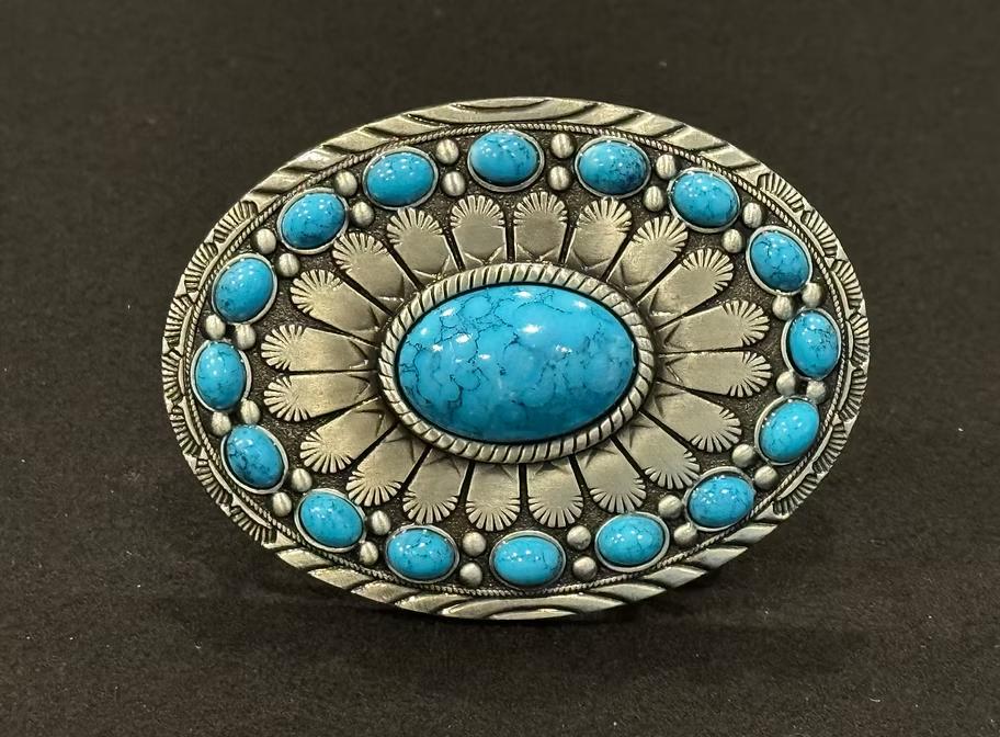 Oval silver cowboy buckle with intricate engraving and turquoise stones.