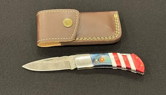 A pocket knife with American flag colors next to a brown holder.