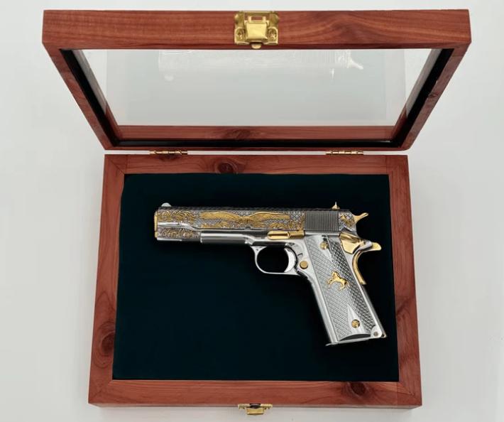 Engraved semi-automatic handgun photographed on a neutral background