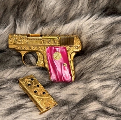 Custom engraved 24K gold-plated firearm with Kirinite pink pearl grips on display