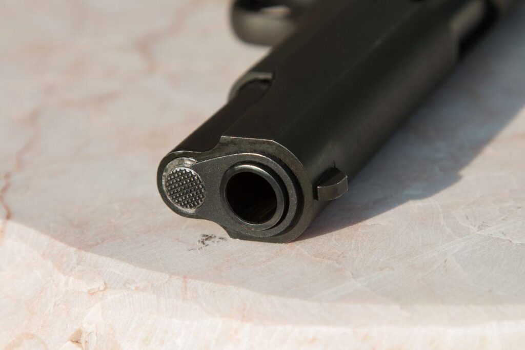 a firearm barrel on a surface, highlighting the metal texture